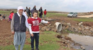 Sağanakta köprü yıkılınca, öğrencileri derenin diğer tarafına sırtlarında taşıyarak geçirdiler