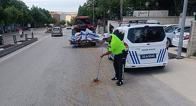 Polis, traktörden düşerek yola saçılan kuzu yemlerini topladı