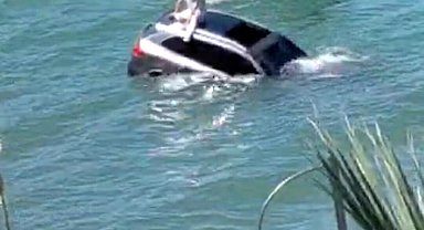 Denize uçan otomobilinin üzerinde oturup yardım bekledi