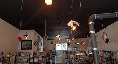 Kitapları, dijital çağa yenilmesine dikkat çekmek için kafenin tavanına astı