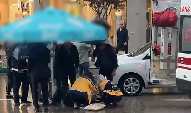 Otomobilin çarptığı yaralıyı yağmurdan korumak için şemsiye tuttular